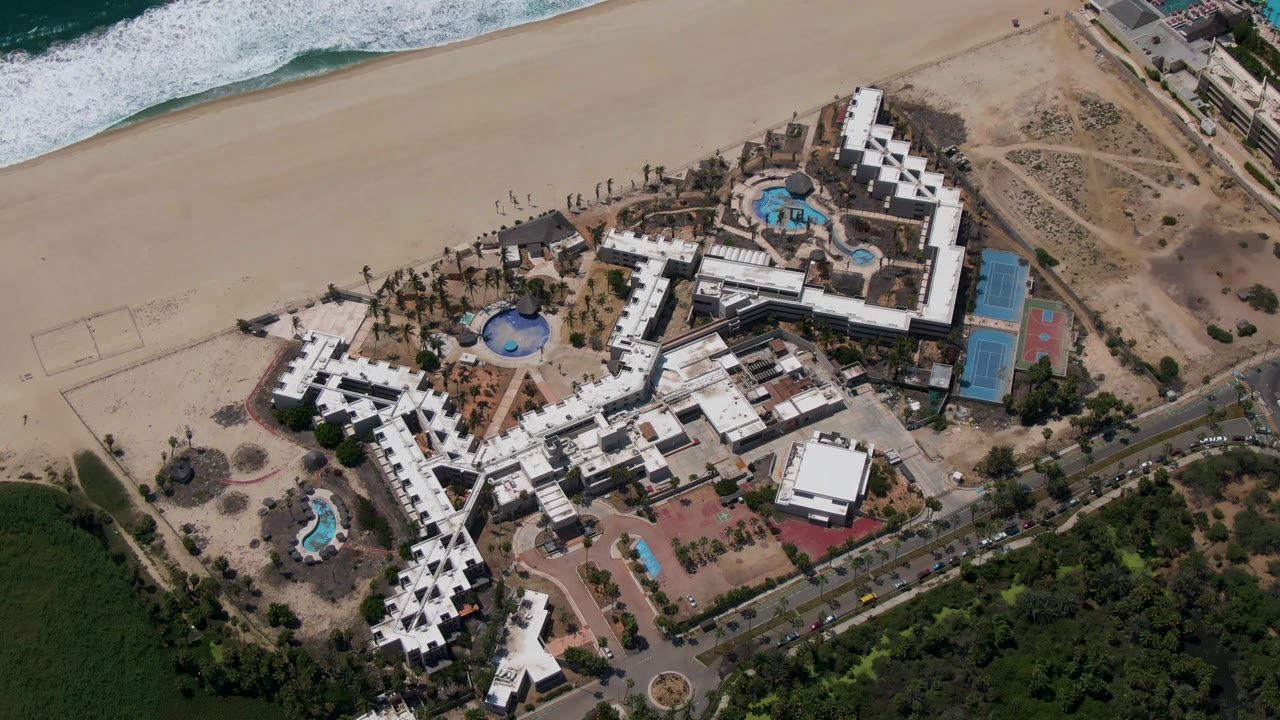 Aerial view of a beachfront resort beside ocean waves and sand