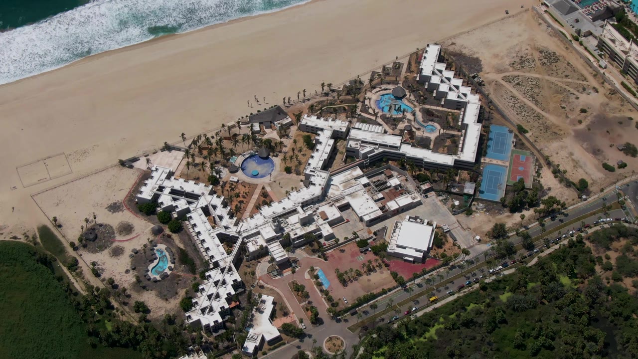 Fourth frame shows the San Jose Del Cabo resort from above with the white building wings, multiple pools, sandy beach, ocean foam, lower road, and no visible people.