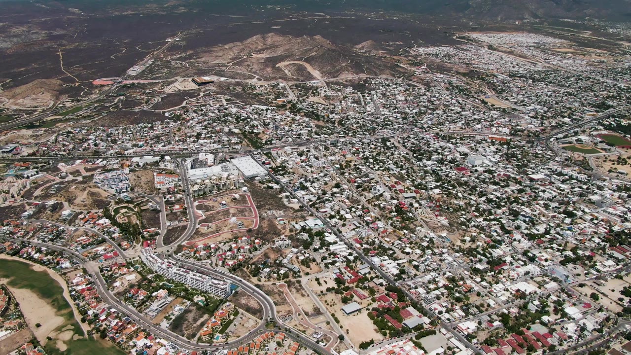 Dense residential area below dry mountains with winding streets.