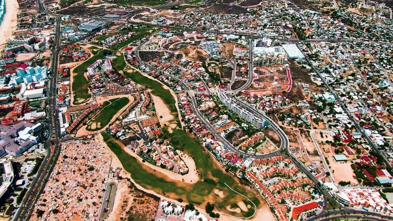 Drone view of coastal highway, beach, and dense urban blocks