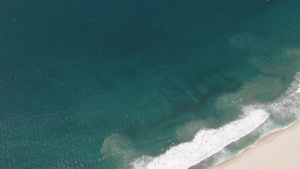 White foam line advances diagonally toward the sandy beach.