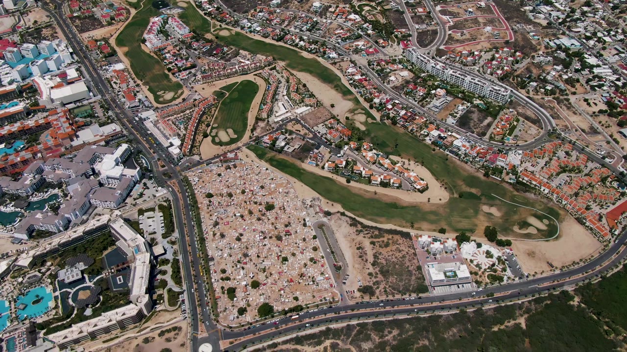 Overhead cityscape with golf greens, roads, homes, and dry lots.