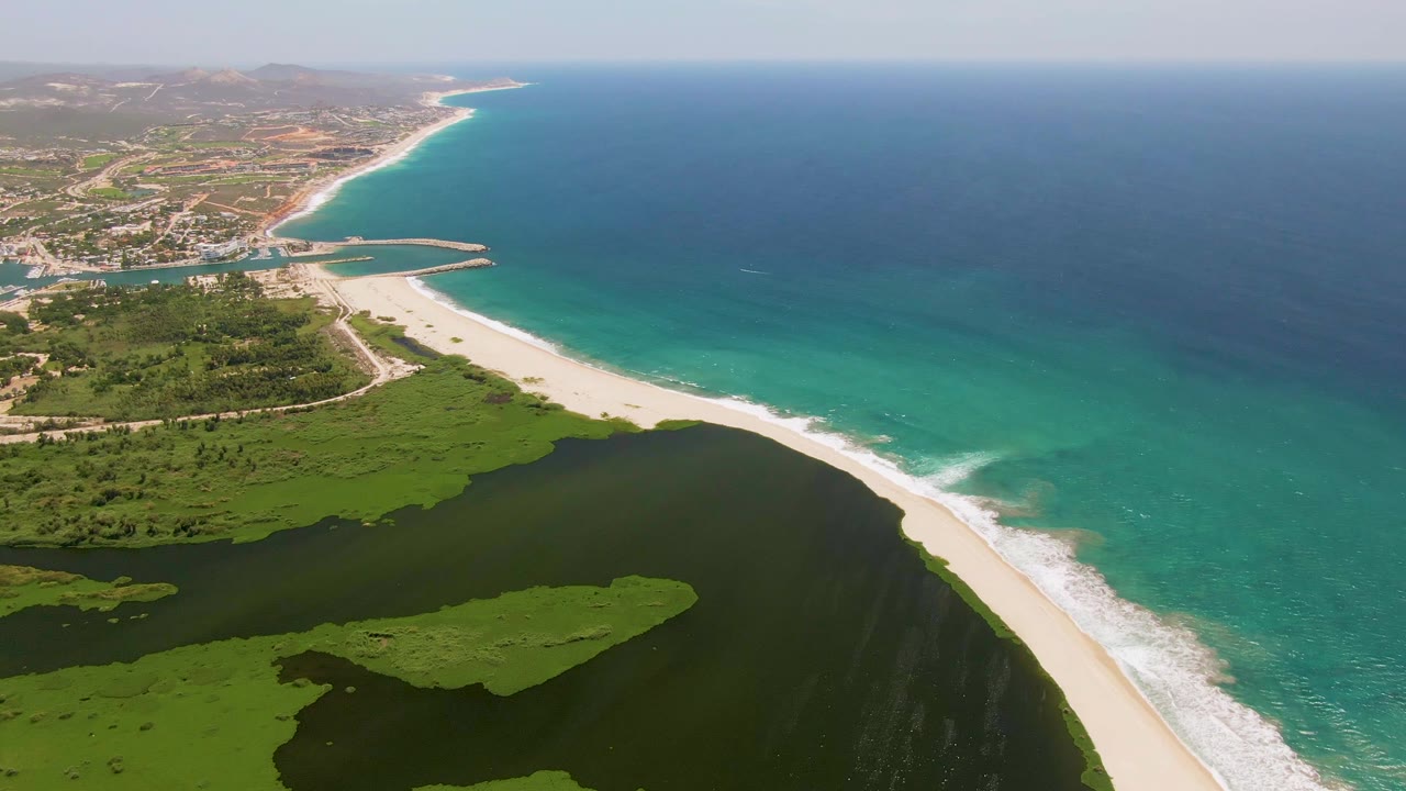 Wide aerial coastline with wetlands, beach, surf, and settlement