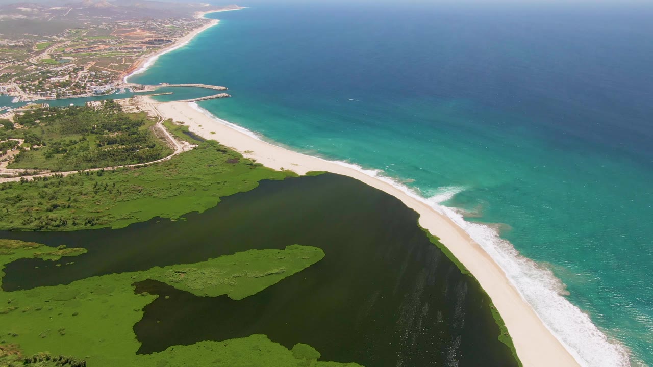 Coastal aerial over lagoon and beach with waves breaking onshore