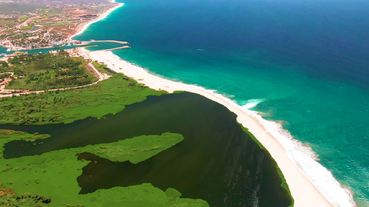 At one second, the San Jose del Cabo shoreline remains centered, with white surf tracing the beach edge and no visible people on the sand or water.