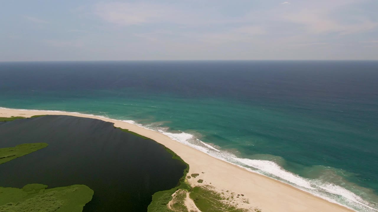 Wide aerial coastline with lagoon, beach, and ocean horizon