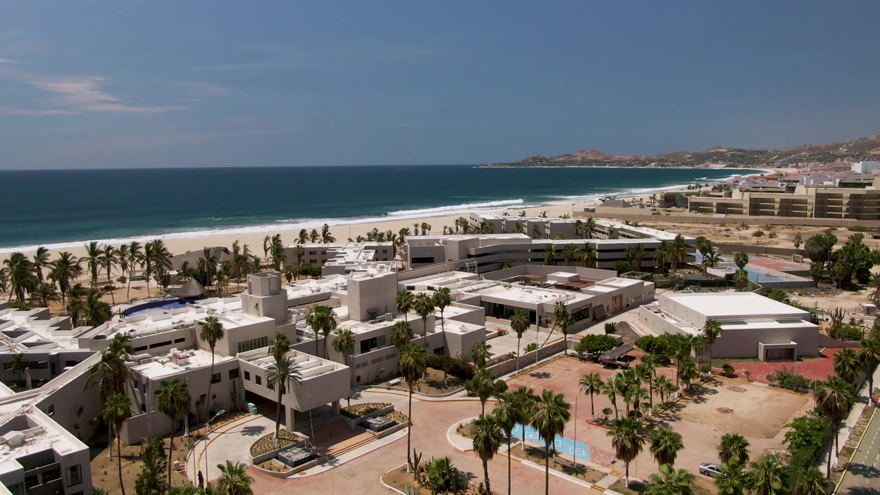 Aerial view of beachfront resort buildings beside palm trees and ocean