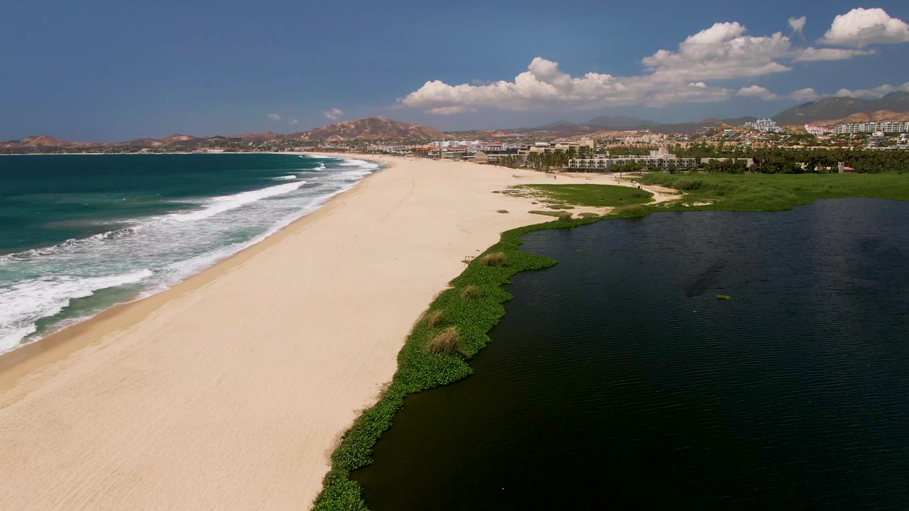 Wide beach with rolling surf beside a lagoon