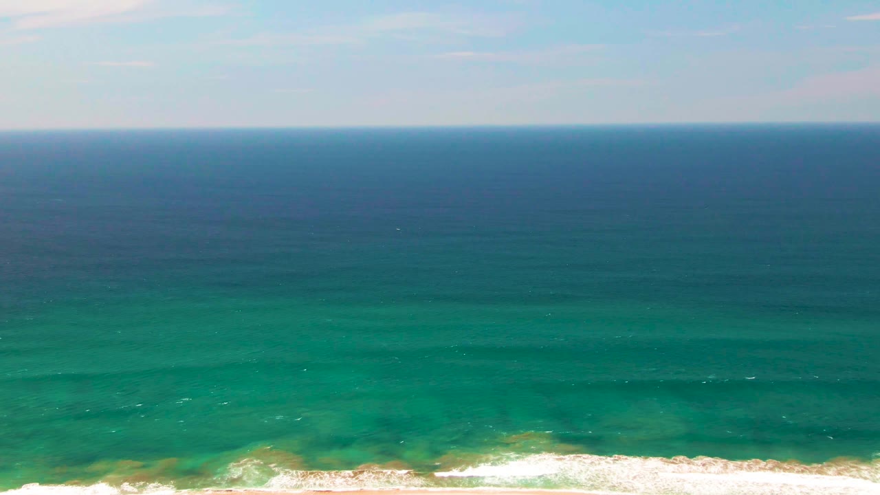 San Jose Del Cabo ocean view with a level horizon, green-blue water across the frame, and a narrow foamy break at the lower right, no visible people.