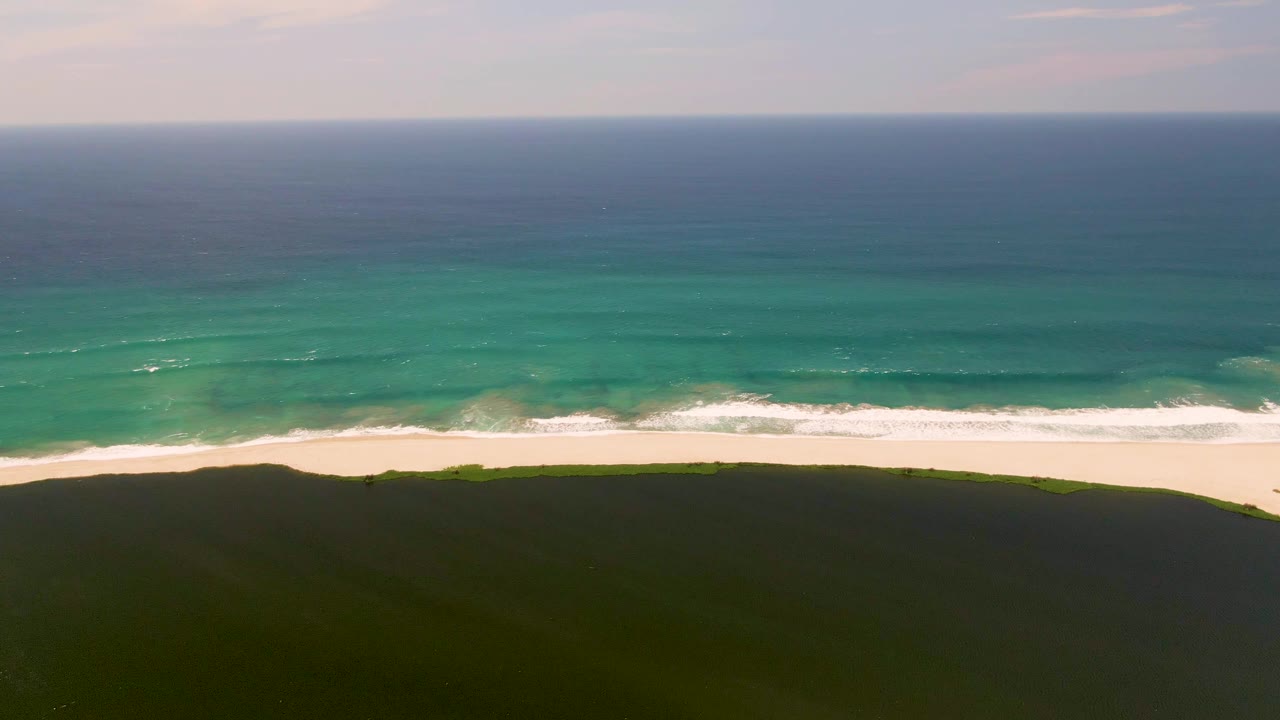 One second in, the surf line sits slightly closer to the white sand in San Jose del Cabo, with green dune foreground and no visible people.