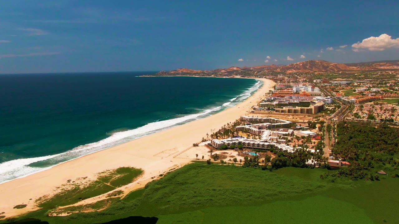 Fourth frame shows the San Jose Del Cabo shoreline from a similar aerial angle, with the ocean filling the left side, the beach cutting diagonally through the center, built-up coast at right, and no visible people.