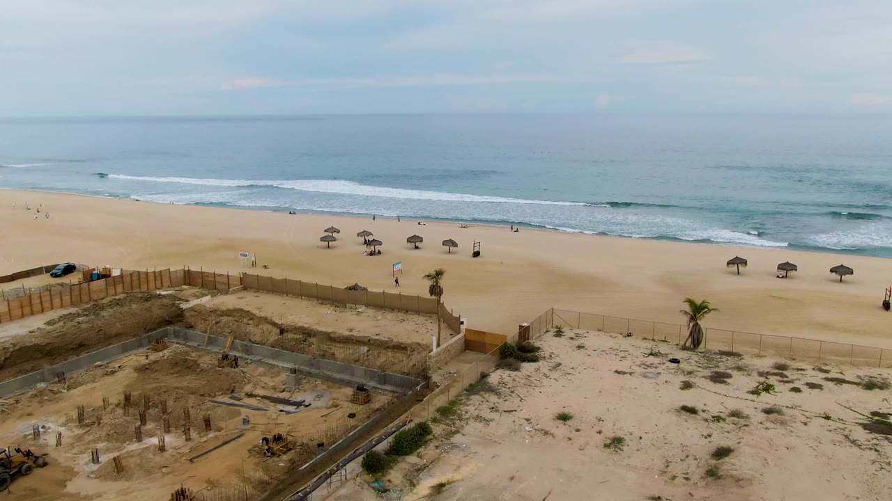 Beach construction area with umbrellas and surf in the distance.