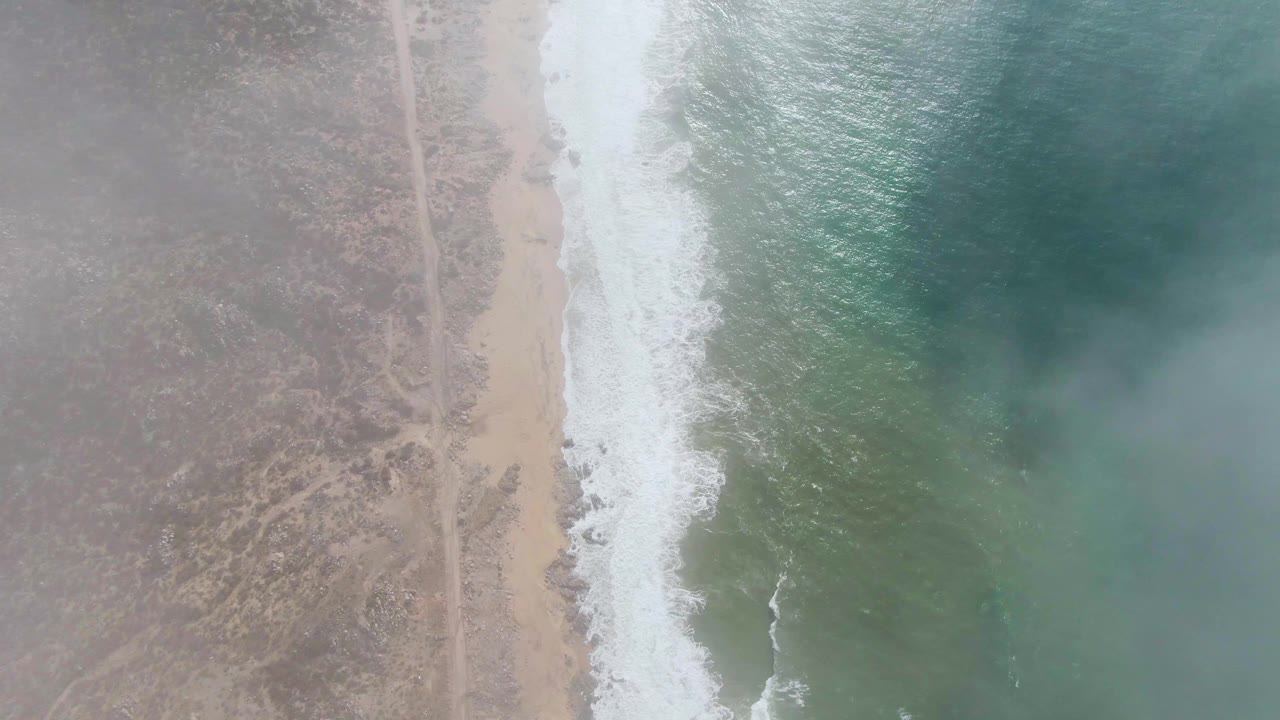 At 0:03, the Punta Gordo coast appears from above with the inland dirt road more noticeable, surf breaking along the sand, and no visible people in frame.