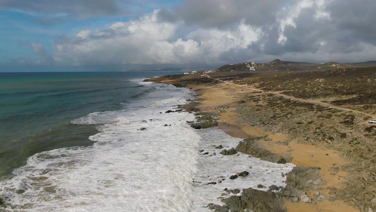 White waves spread along the rocky shoreline under heavy clouds.