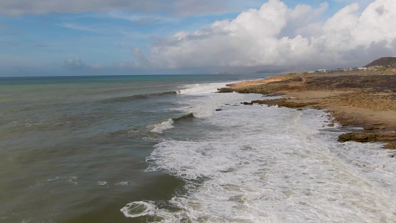 Aerial view of waves breaking along a sandy and rocky coast
