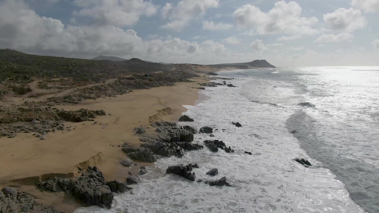 At Punta Gorda, Baja California Sur, the aerial angle shows more rocky outcrops in the lower beach area as bright surf pushes shoreward, with no visible people.