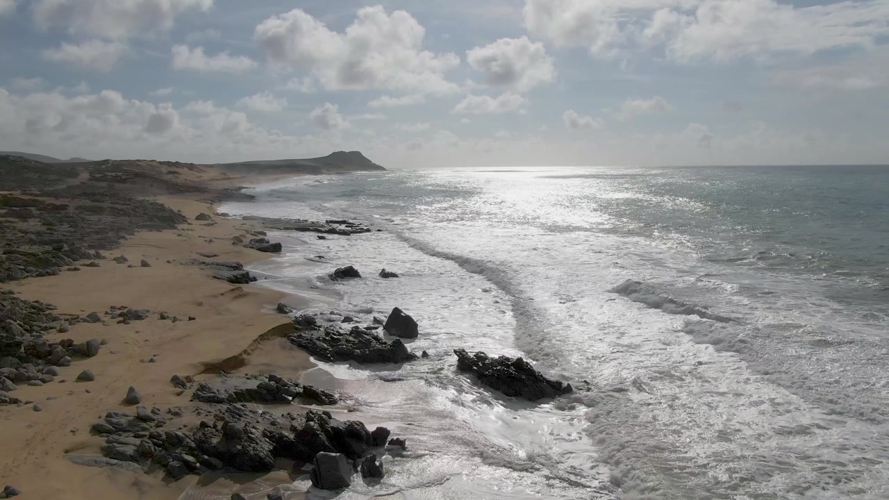 Aerial view of waves breaking on a rocky sandy shoreline