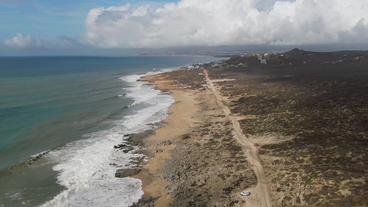 Surf and beach road with a small vehicle visible