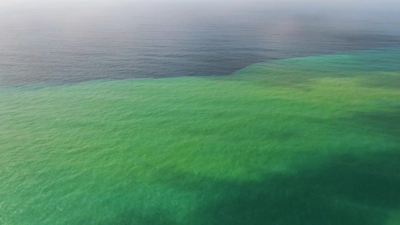 Punta Gorda lagoon water fills most of the frame in green tones, with a darker ocean band across the background and no visible people.