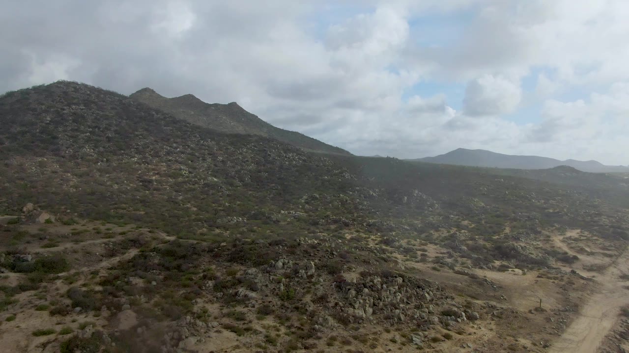 Arid valley road below dark rocky hills
