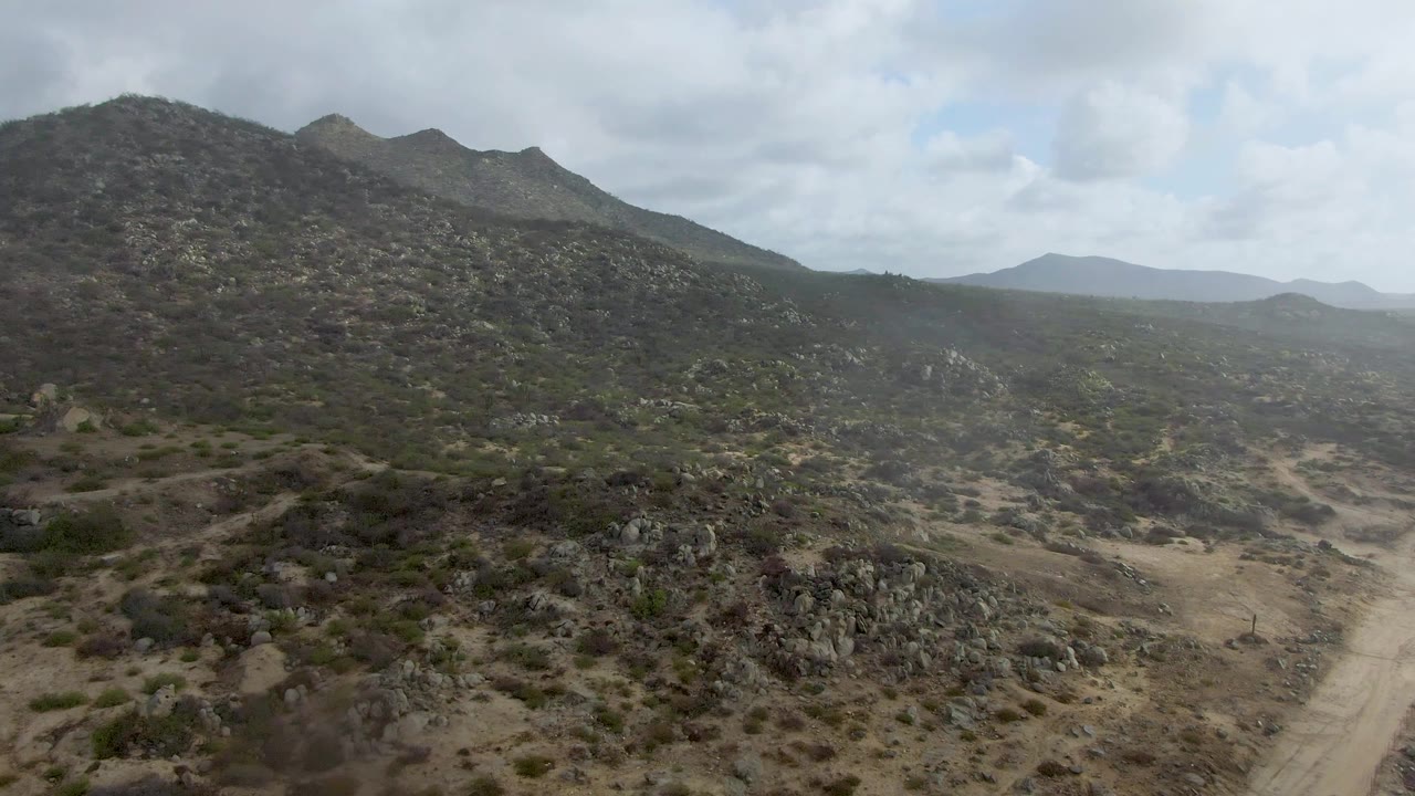 Rocky hillside and dirt road across dry brushland.