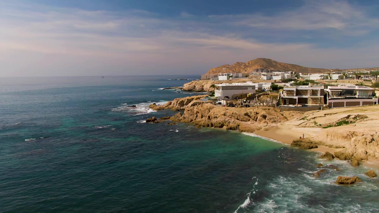 Ocean surface and rocky beach below low coastal structures