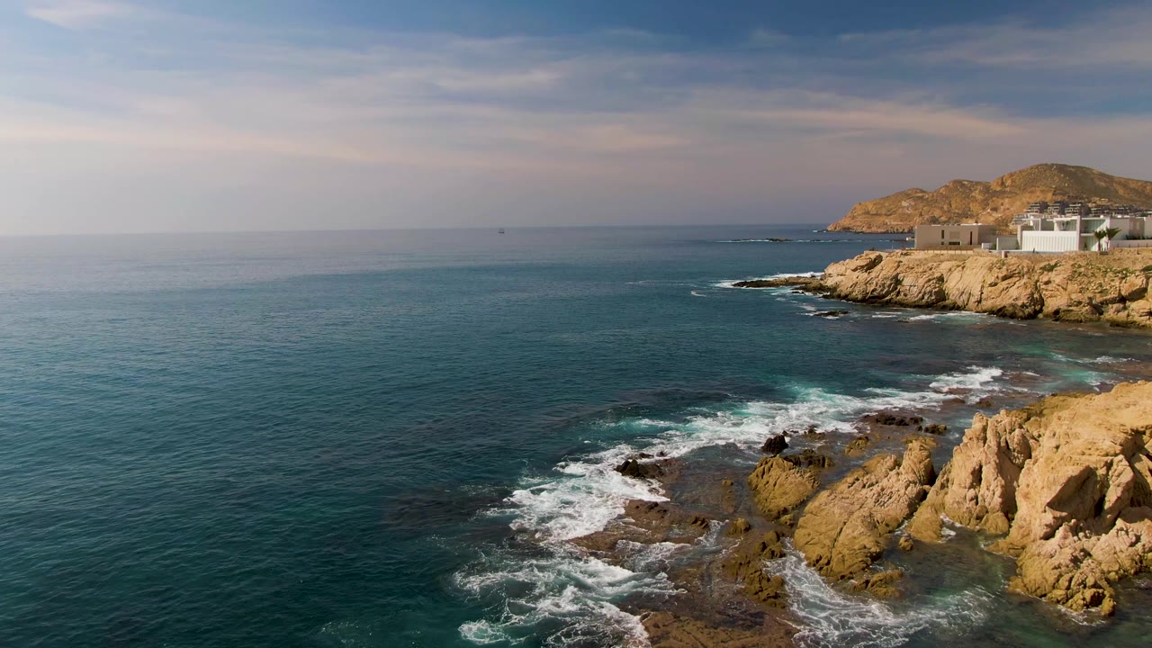 Foam spreading over rocks below an open ocean horizon