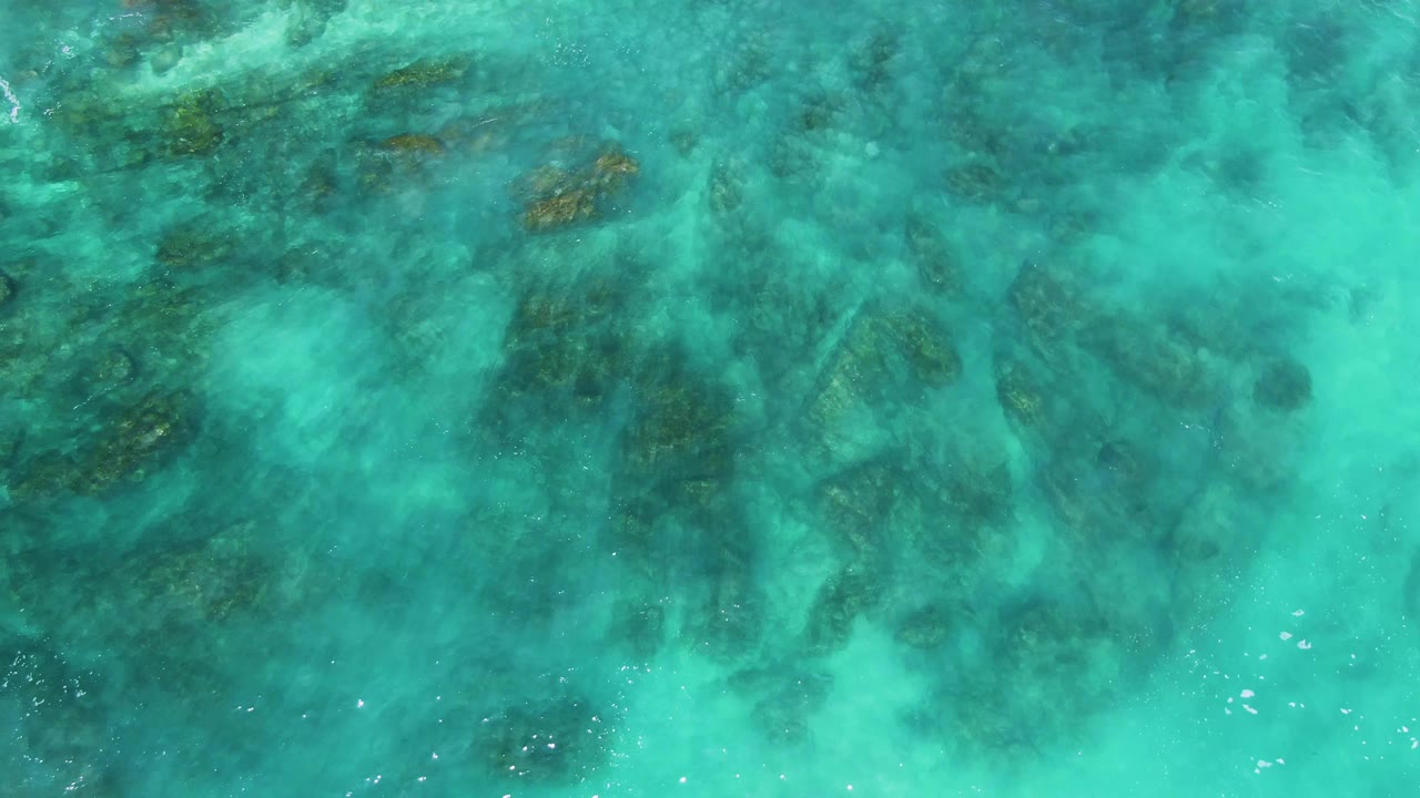 Turquoise water over dark submerged rocks