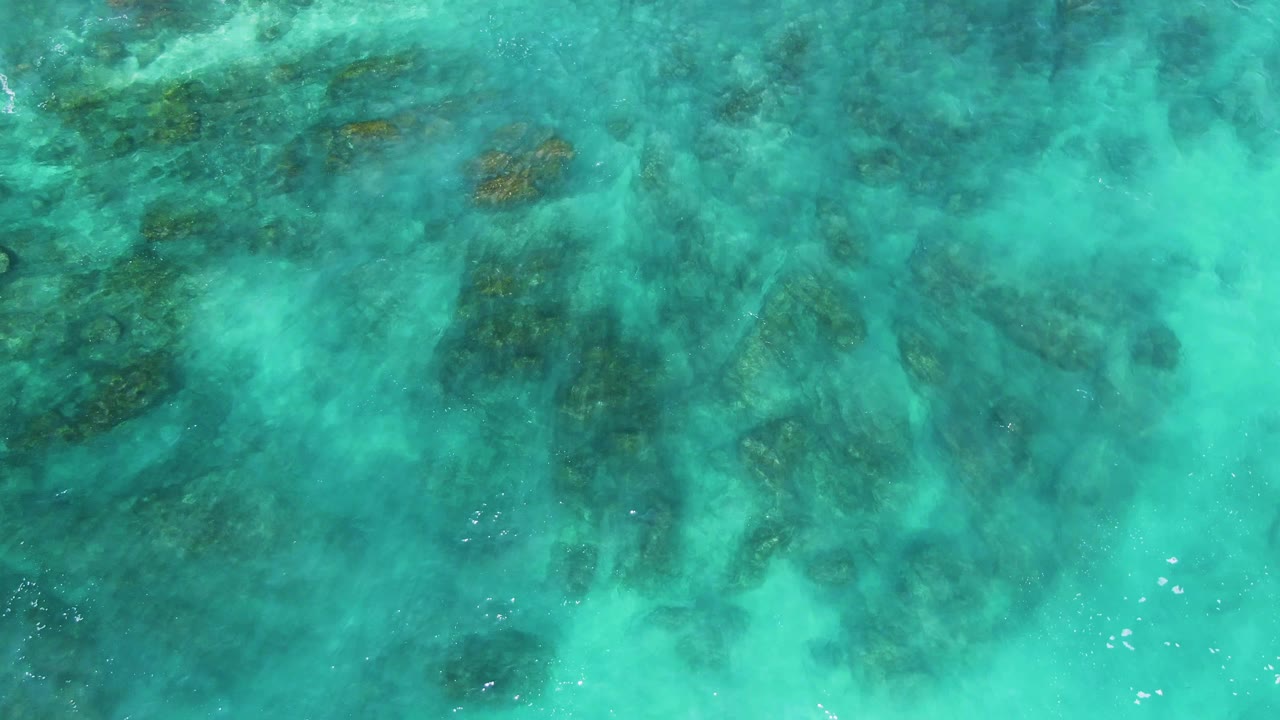 Clear blue-green water fills the frame at El Tule Los Cabos, with darker underwater patches softened by surface ripple and no visible people.