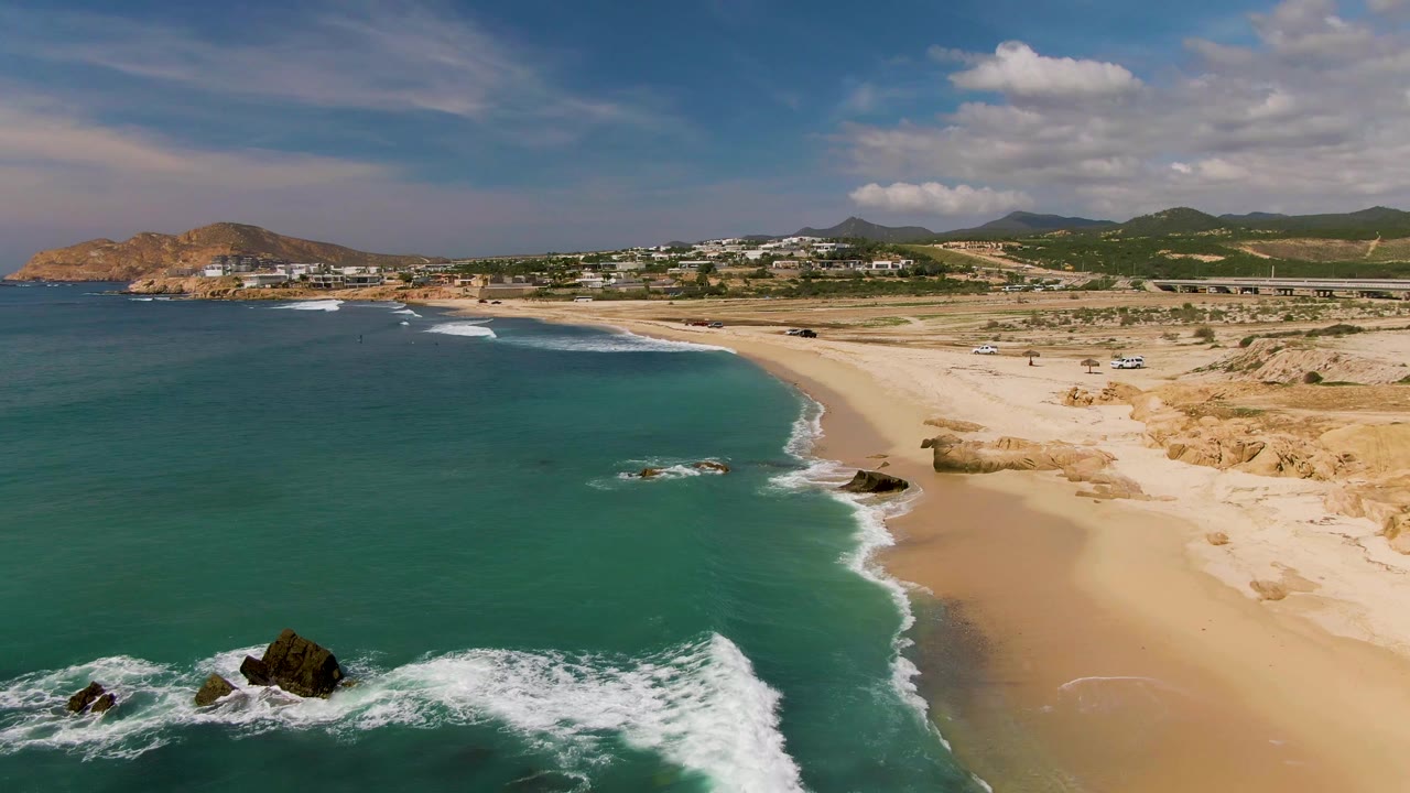 Aerial coastline with rocks in the foreground and beach curving inland.