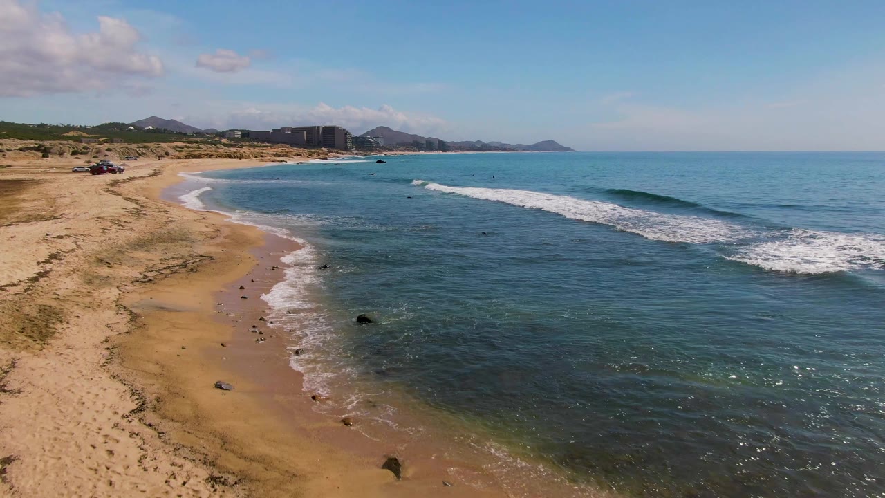 Aerial coastline with surf breaking toward sandy shore