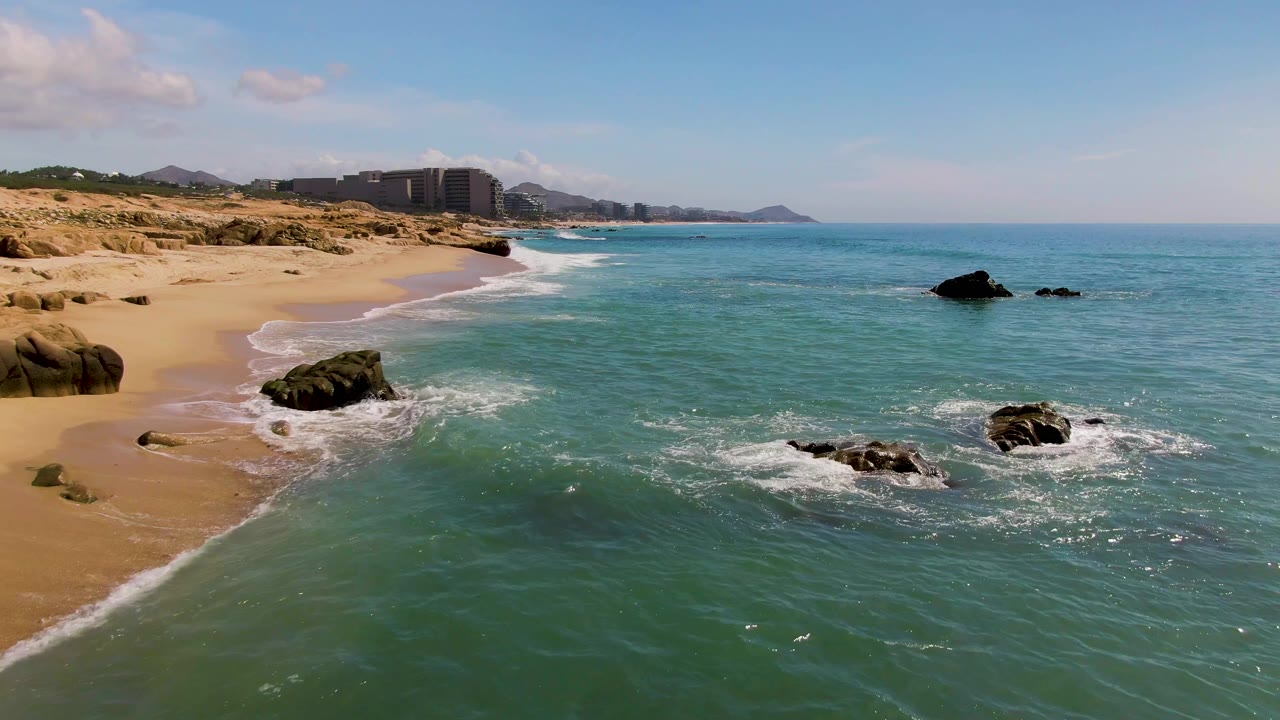 Foam breaking around beach rocks near sandy shore