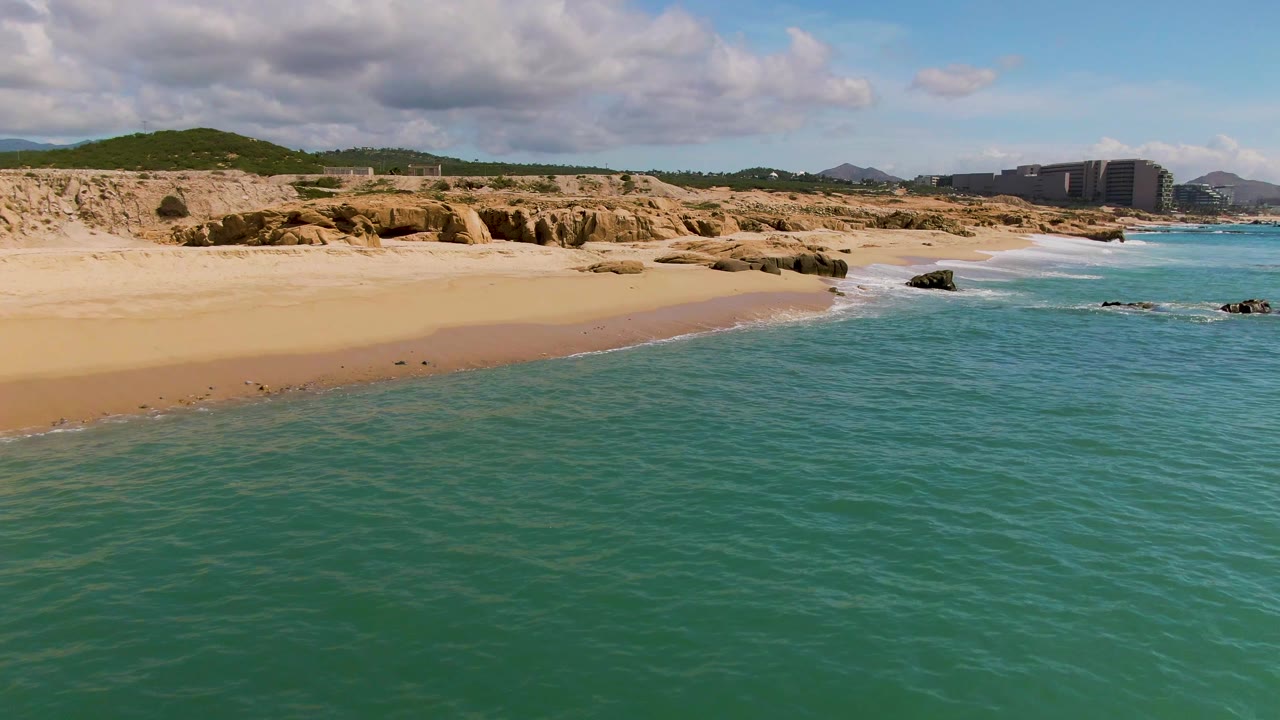 Turquoise water beside sandy beach and rocky coast