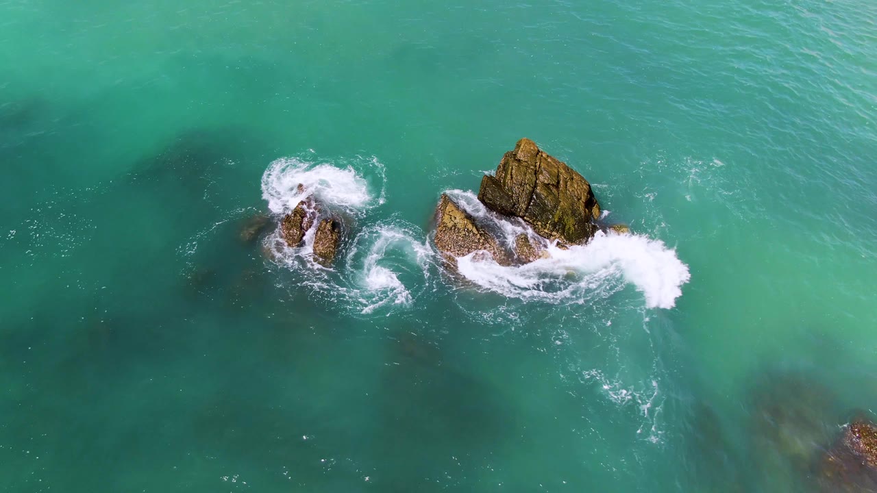 Turquoise ocean water and white waves around rocky outcrops