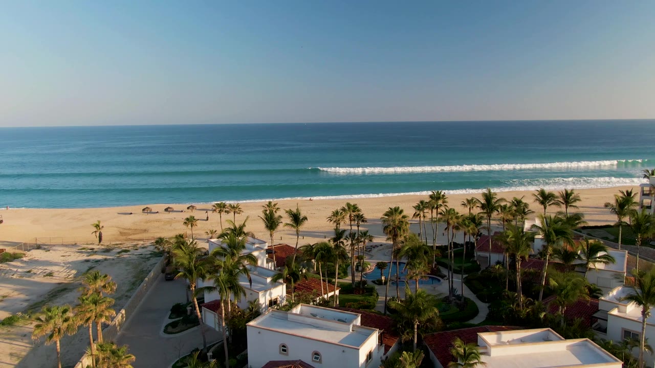 Aerial view of beach, palms, white homes, and calm ocean