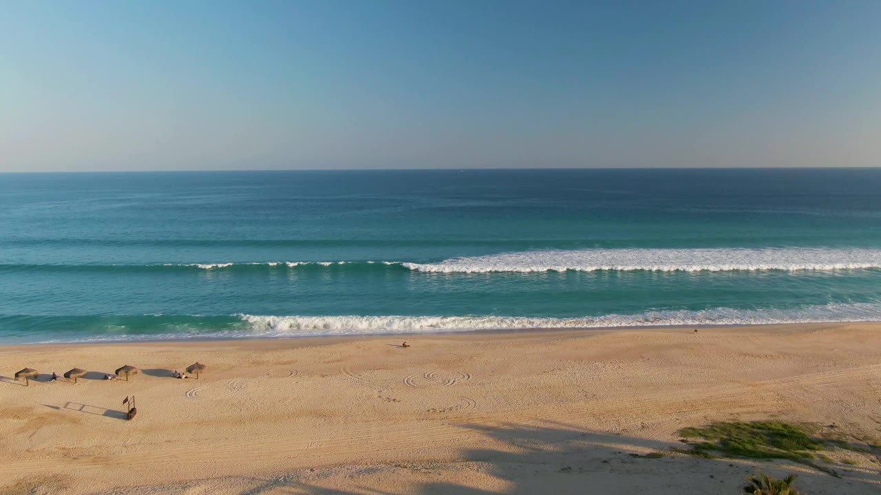 Beach and surf with palm shadows across the sand