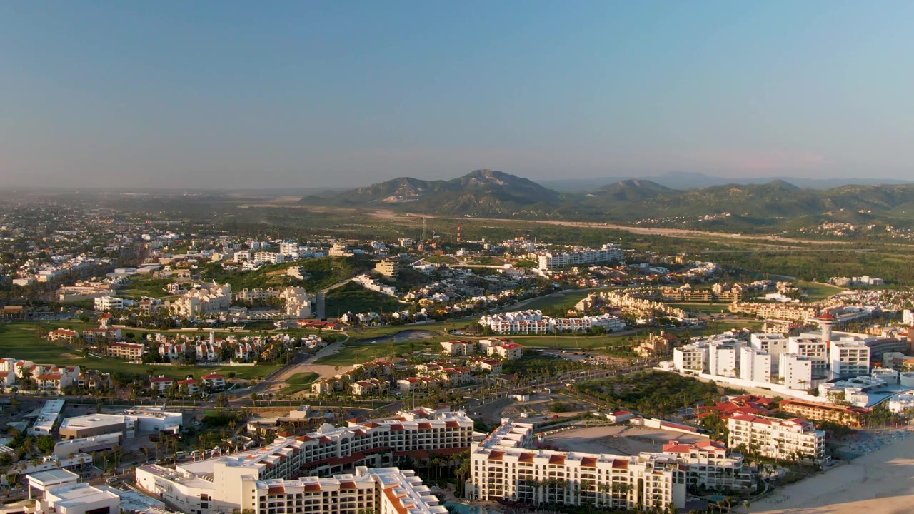 Aerial coastal cityscape with buildings, beach, town, and distant mountains