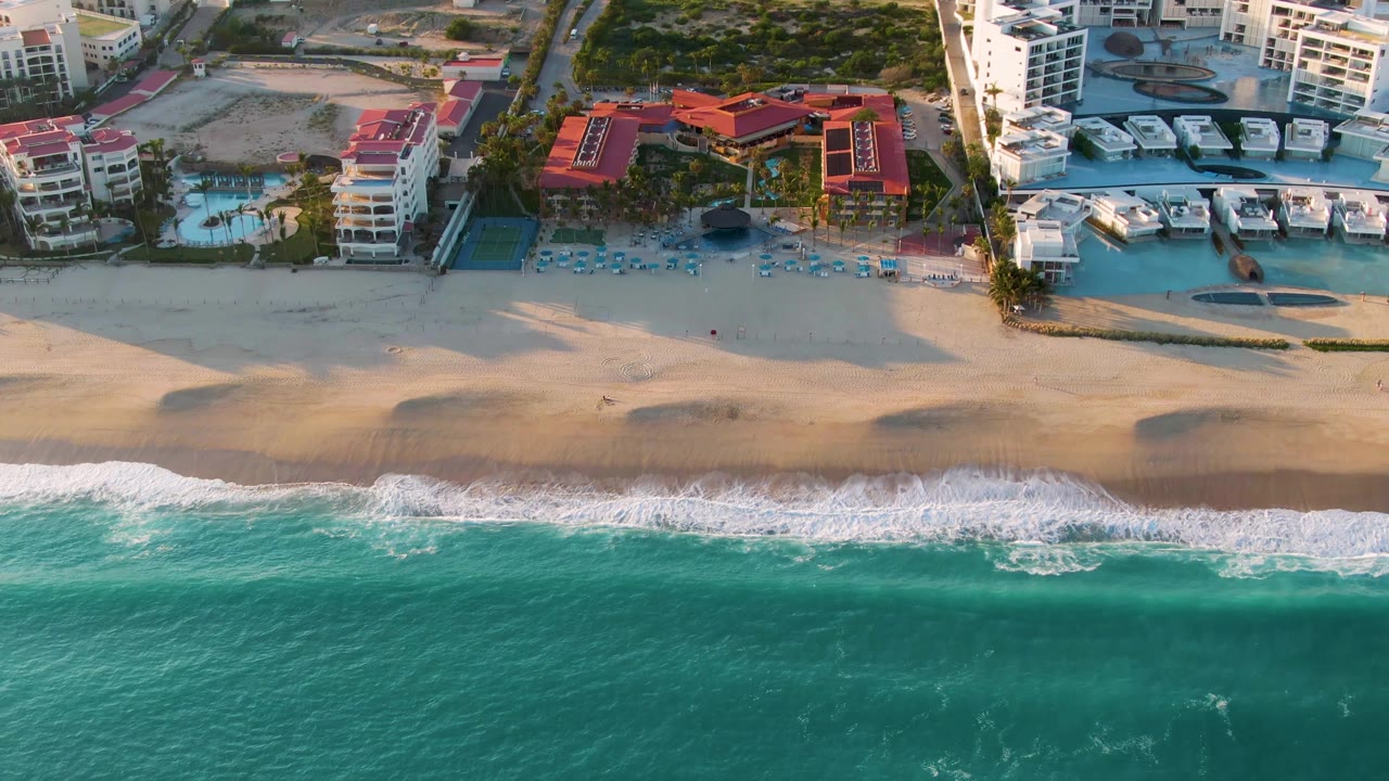 Overhead coastline with breaking waves and beachfront pools