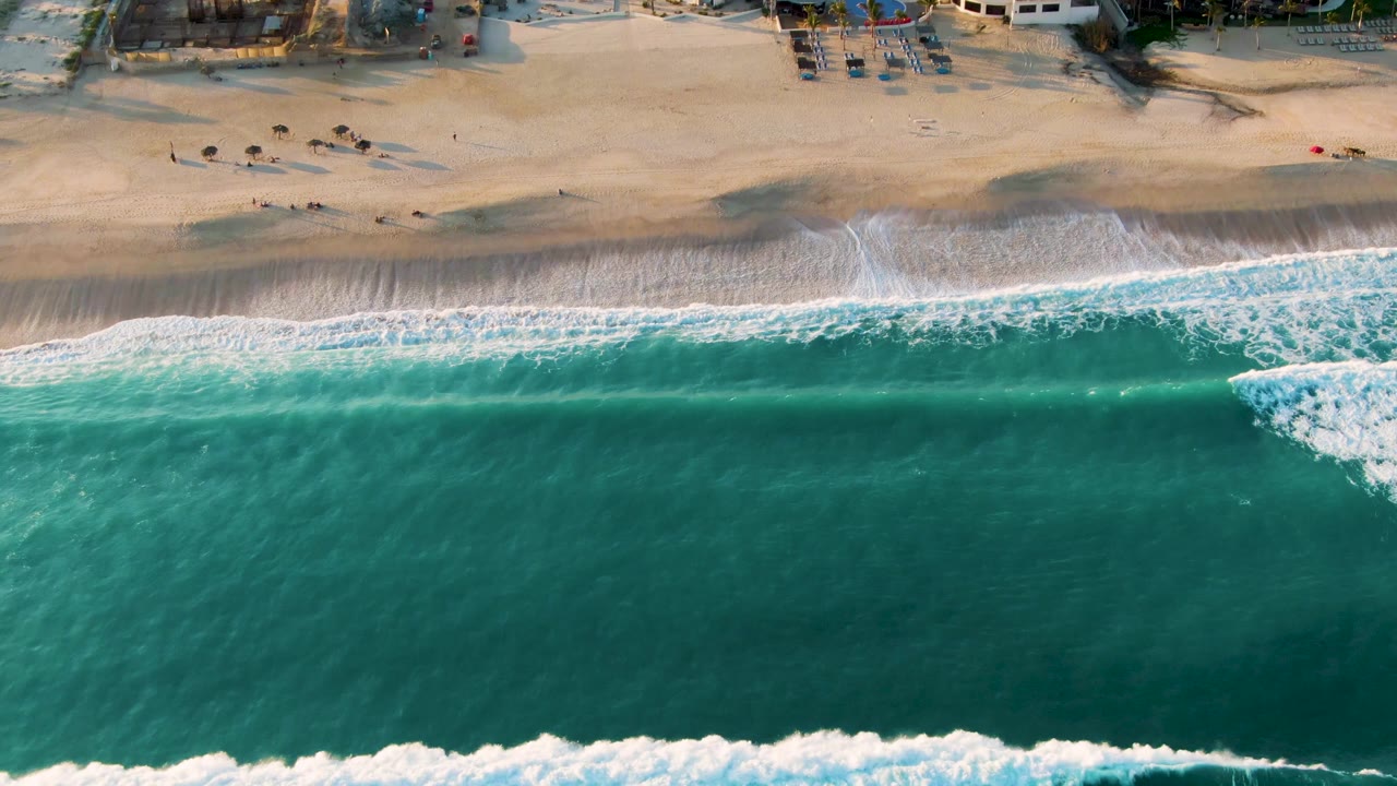 Aerial shoreline with white foam spreading across wet sand
