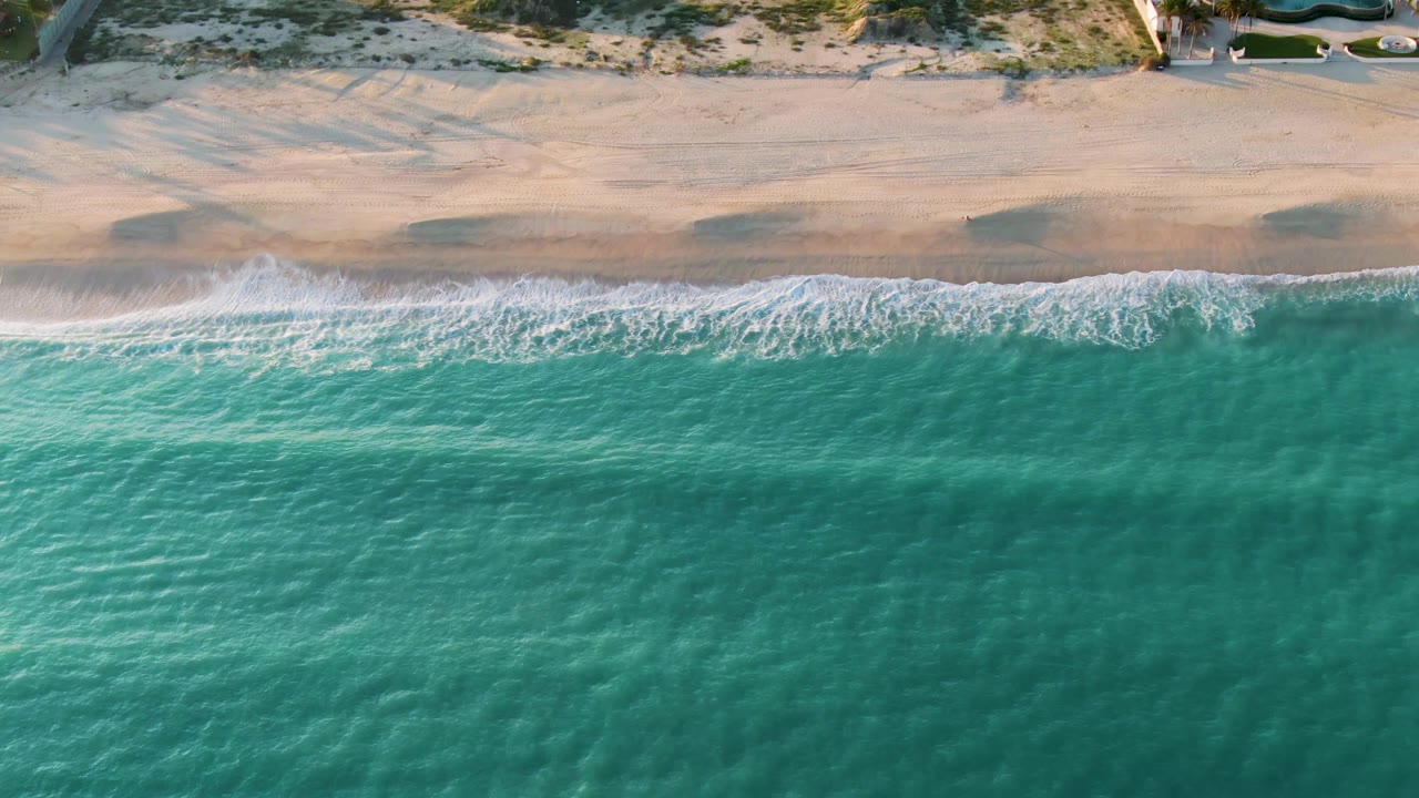 Drone view of empty beach with turquoise water and shore break