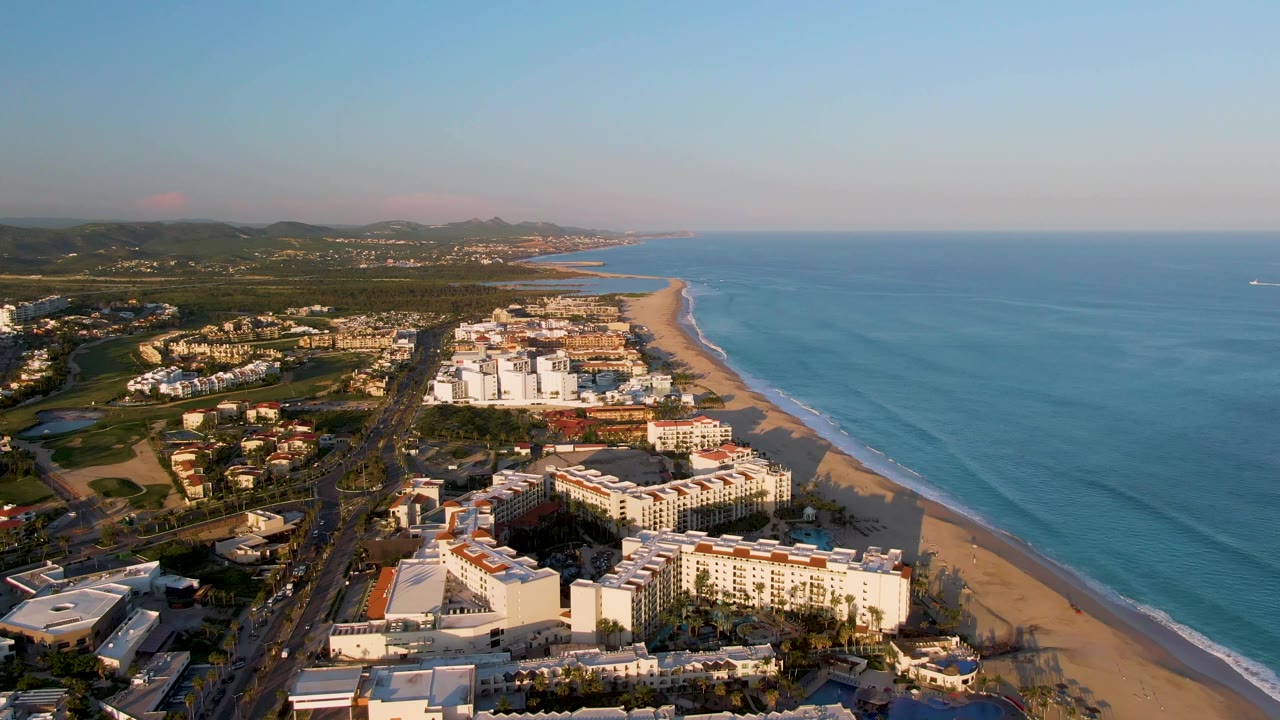 Aerial view of beachfront hotels, a road, and turquoise water