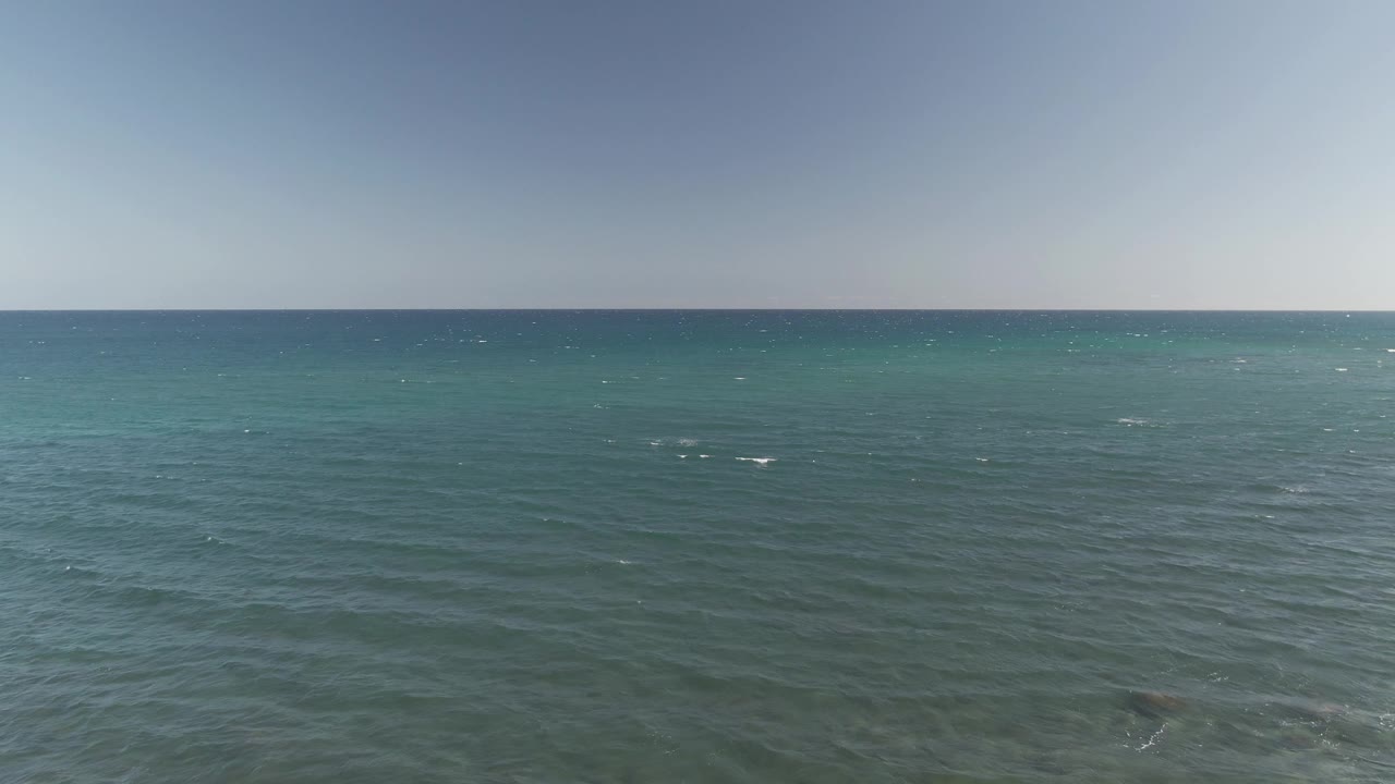 A wide Costa Azul Los Cabos sea view shows rippled blue-green water, small bright whitecaps across the surface, a pale sky band, and no visible people.
