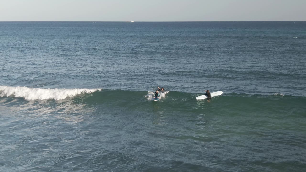 Surfers paddle as whitewater spreads across the wave.