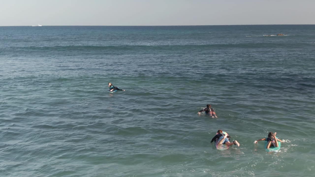 Paddlers on boards spread out across calm ocean swells.