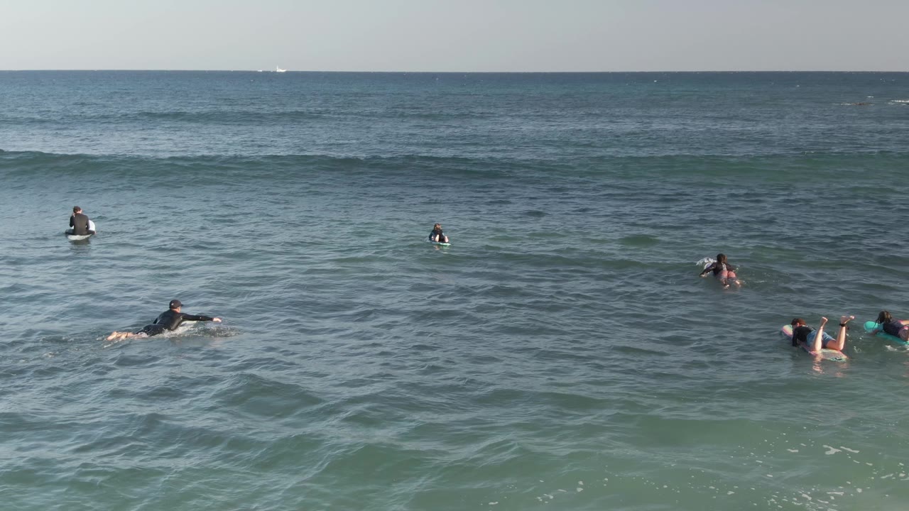 Surfers waiting on boards as a small wave passes