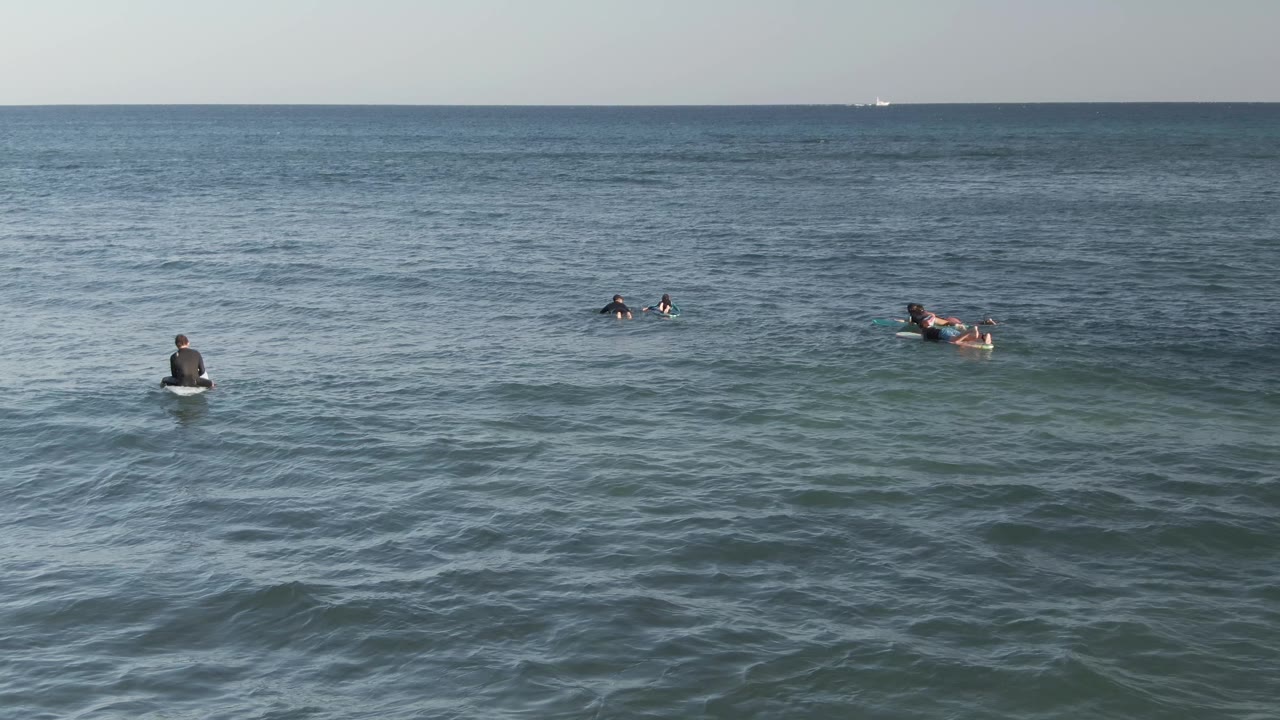 Small group of surfers lying on surfboards offshore.