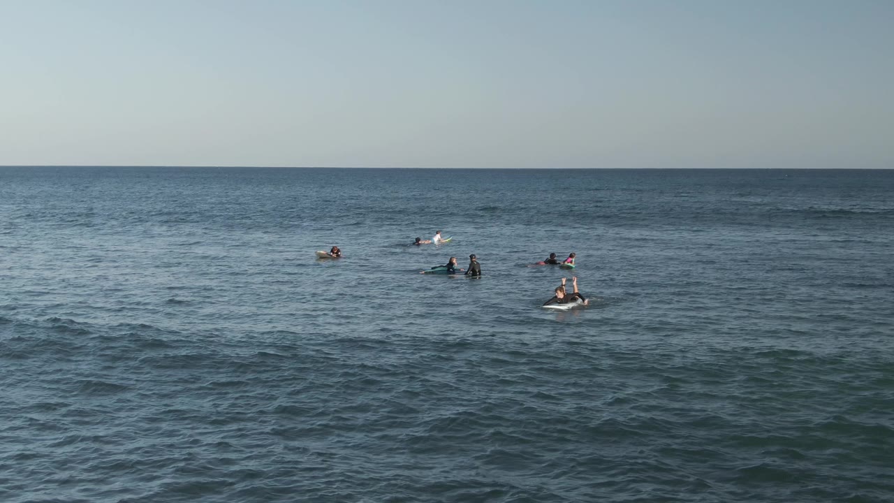 Distant people treading water in calm blue ocean.