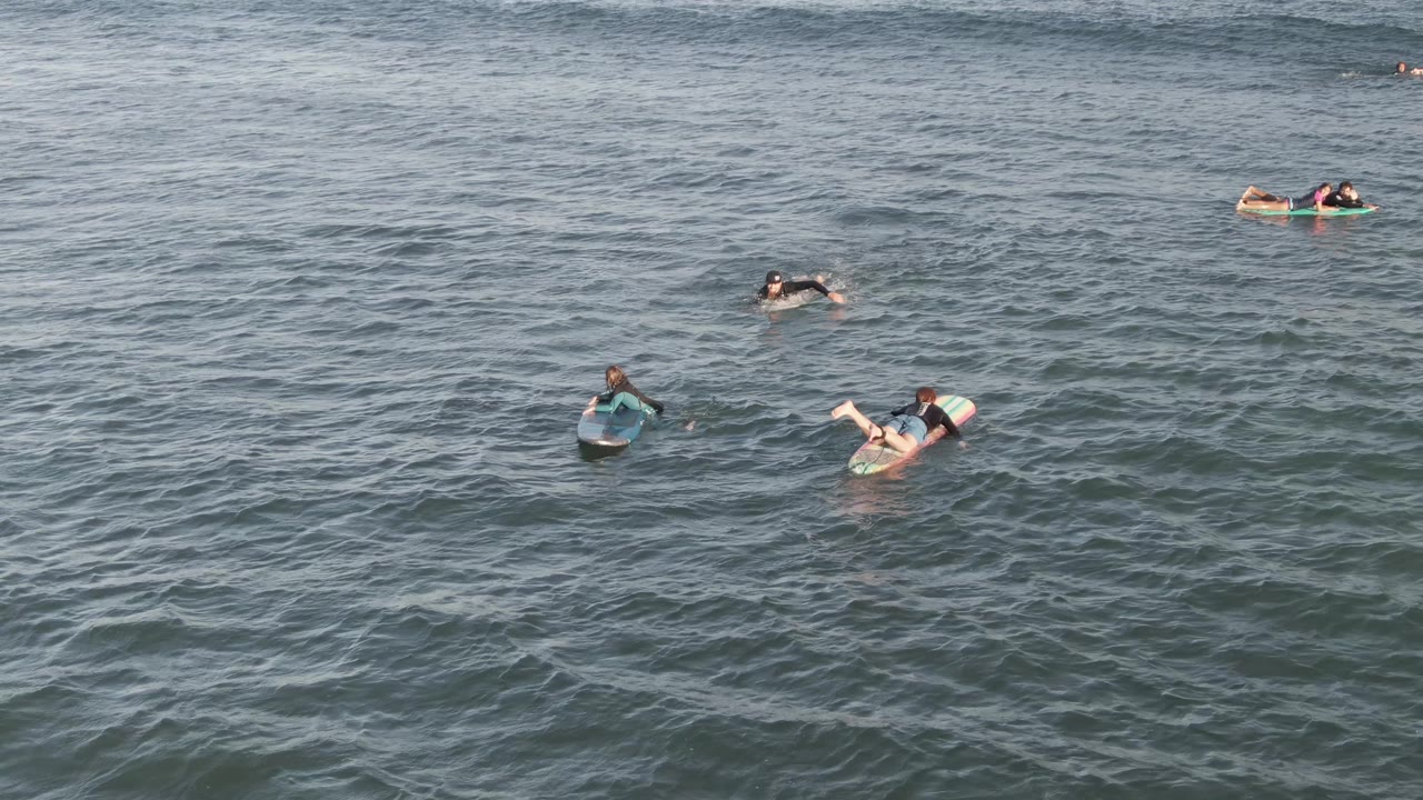 People floating and paddling among gentle ocean ripples.