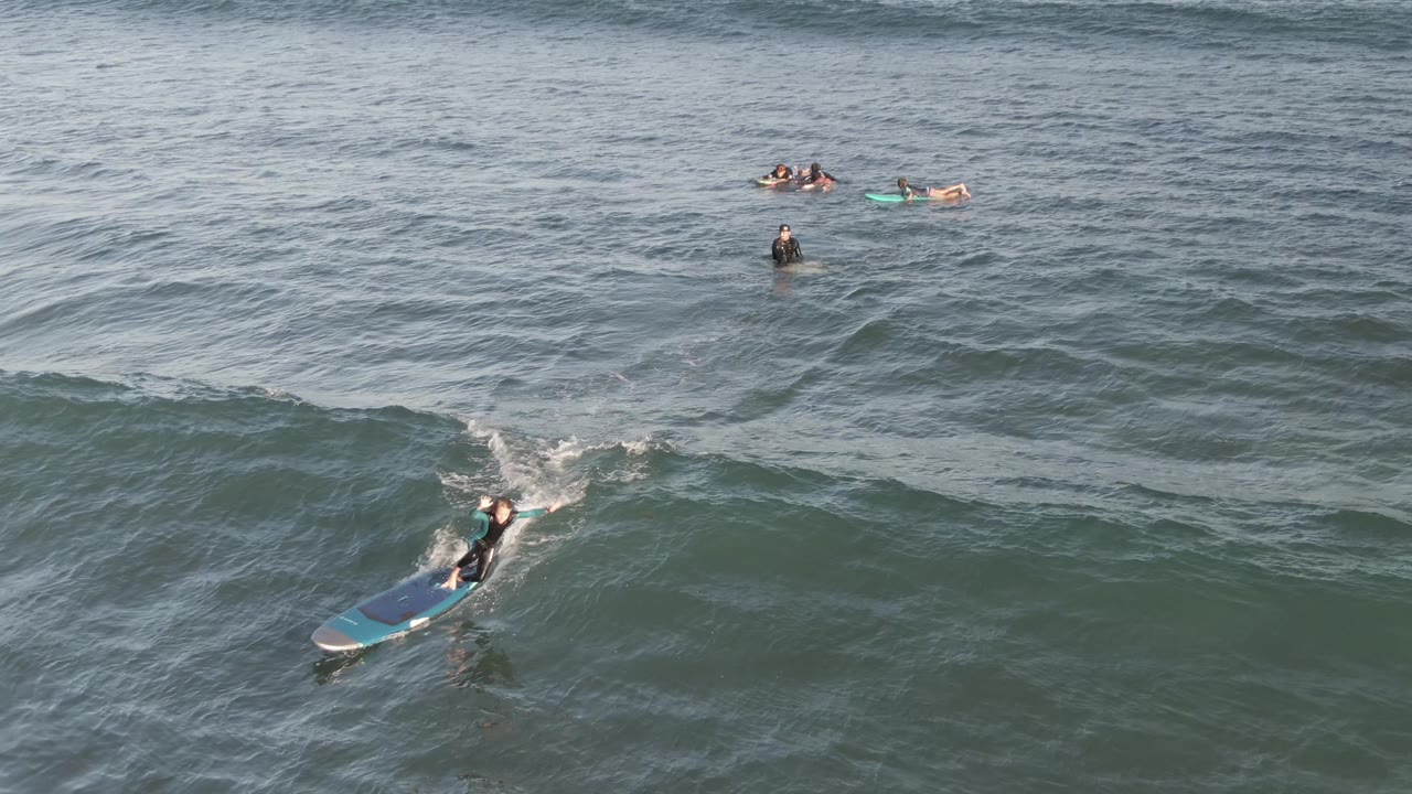 Rider on a blue bodyboard crossing the face of an ocean wave.