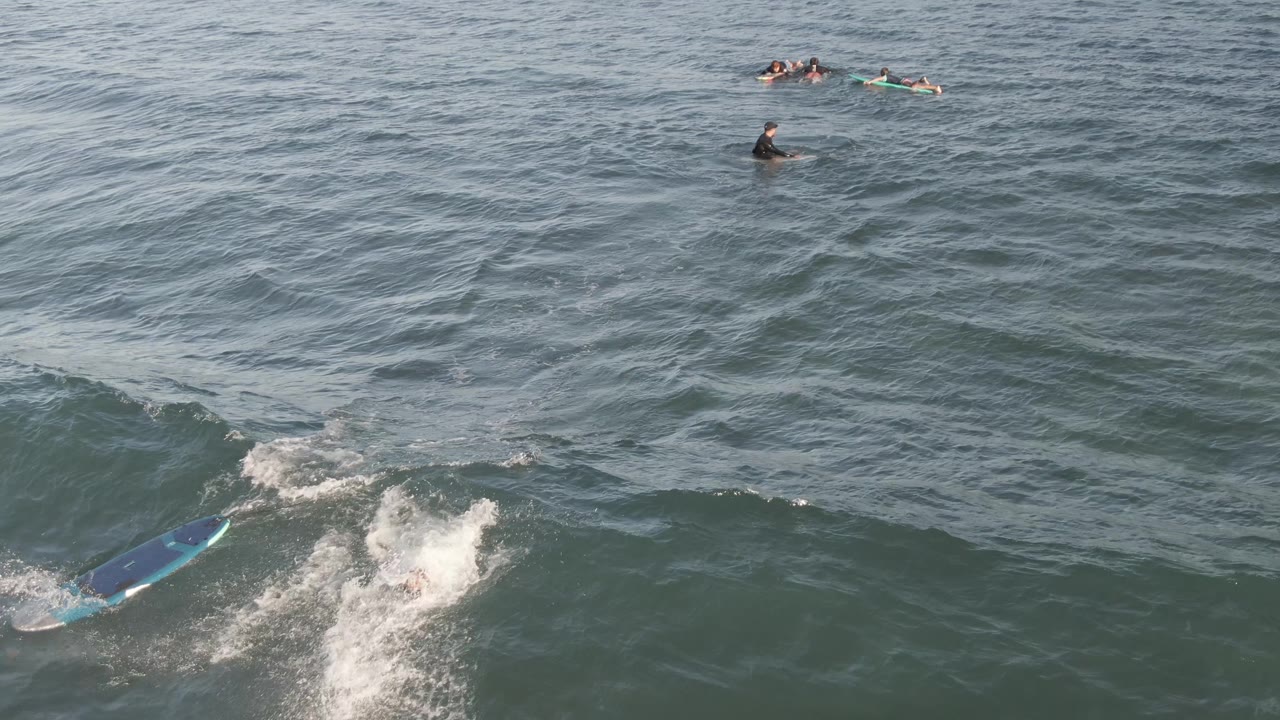 Aerial view in Costa Azul Los Cabos with the blue board sliding ahead of a white splash as the rider falls into the wave.